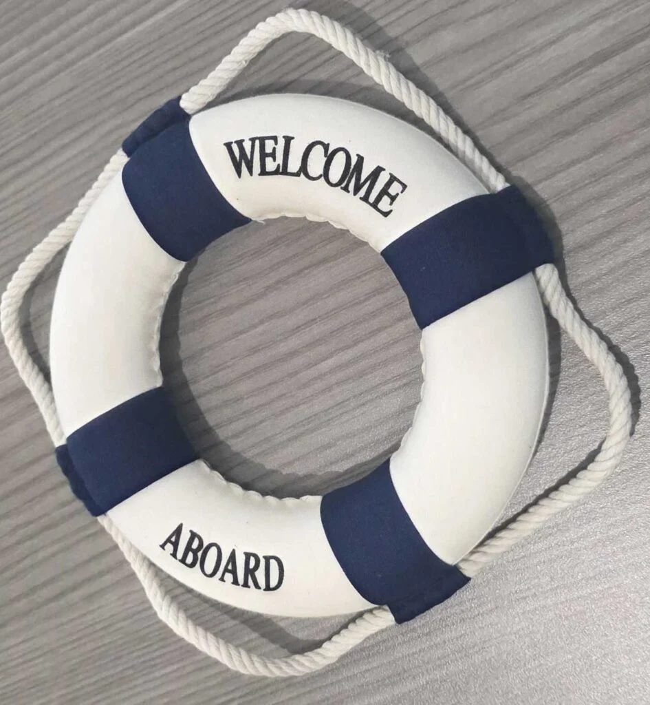 Welcome aboard lifebuoy on a wooden surface.